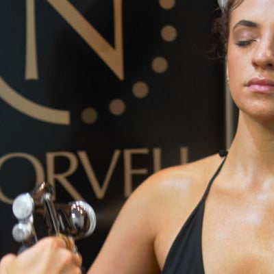 A woman holding a Norvell spray tan gun during a professional sunless tanning session.