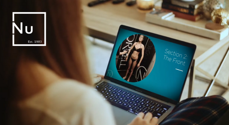 Person using a laptop with the NU Class on the screen, sitting on their couch in front of a coffee table